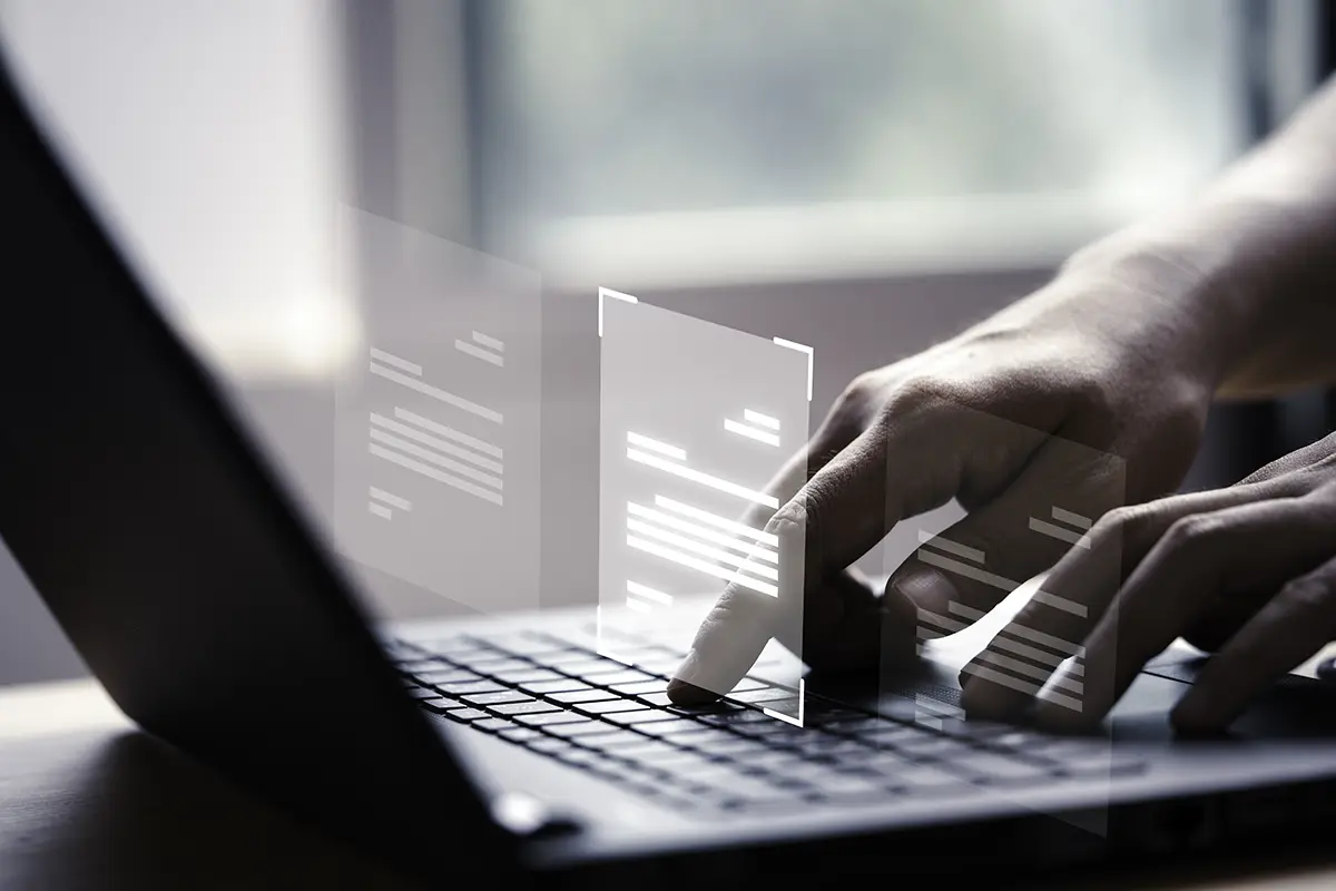 Eine Person tippt auf einem Laptop, während virtuelle Dokumente auf dem Bildschirm schweben, was digitale Dokumentenverwaltung und moderne Arbeitsprozesse symbolisiert.