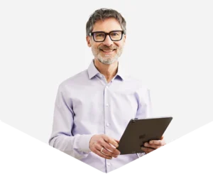 Stephan Merkel aus München hält ein Tablet in den Händen und lächelt in die Kamera.